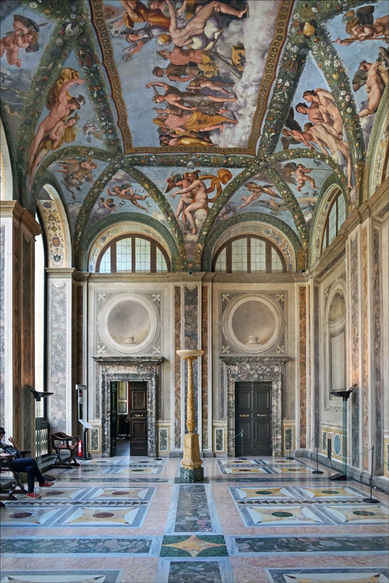 Hall with a marble inlaid floor, carved doorways and a vaulted ceiling covered in frescoes