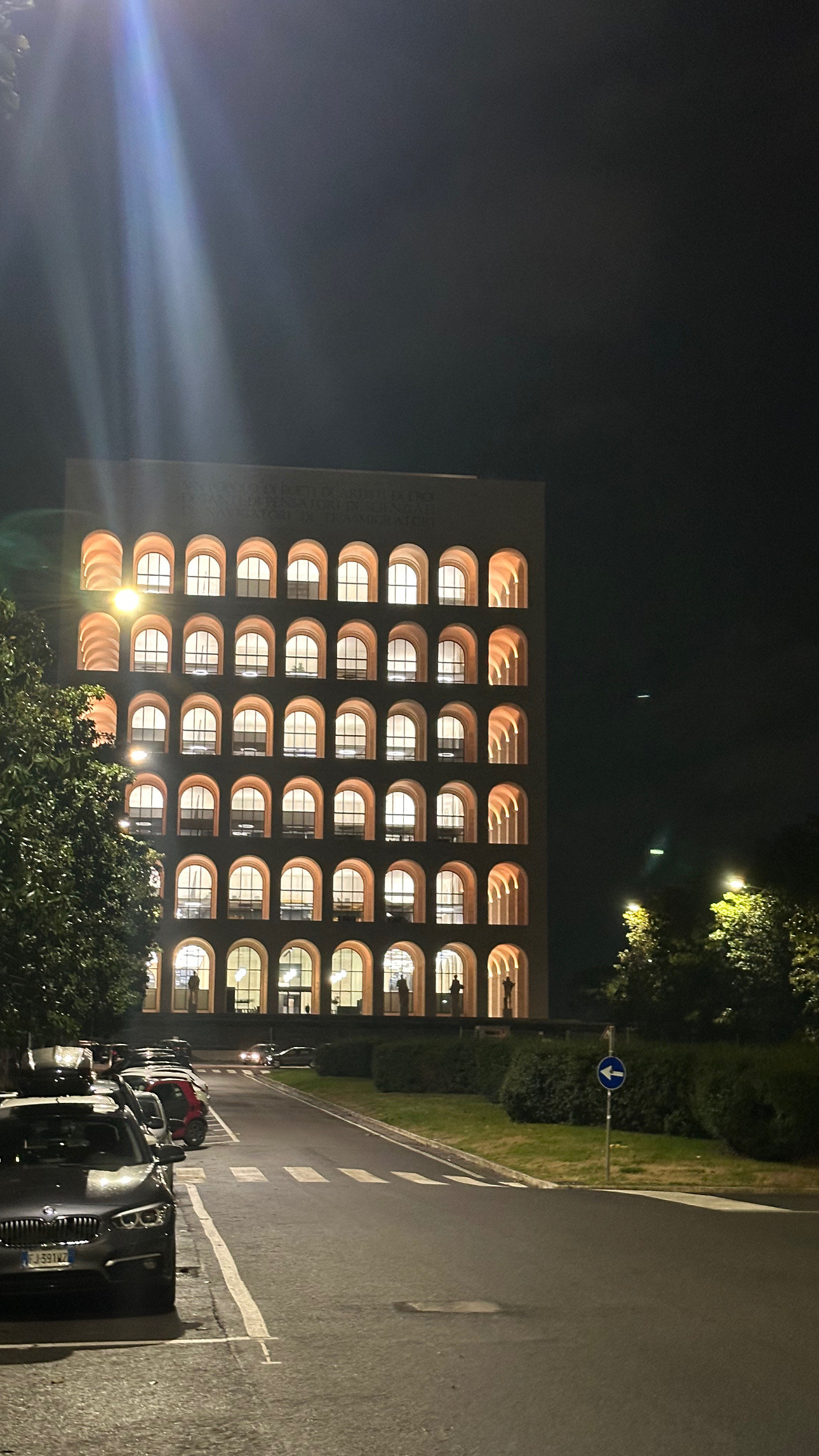 Illuminated arched facade of a rationalist palace glowing against the night sky