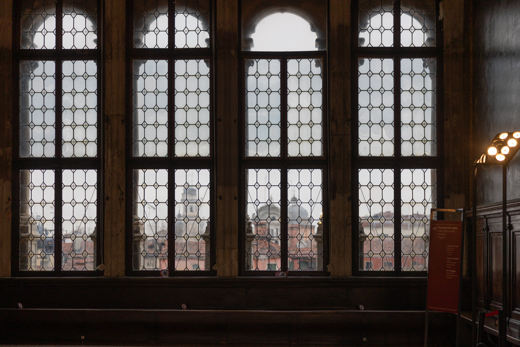Tall leaded-glass windows overlooking Venetian rooftops and domes from inside a historic palace