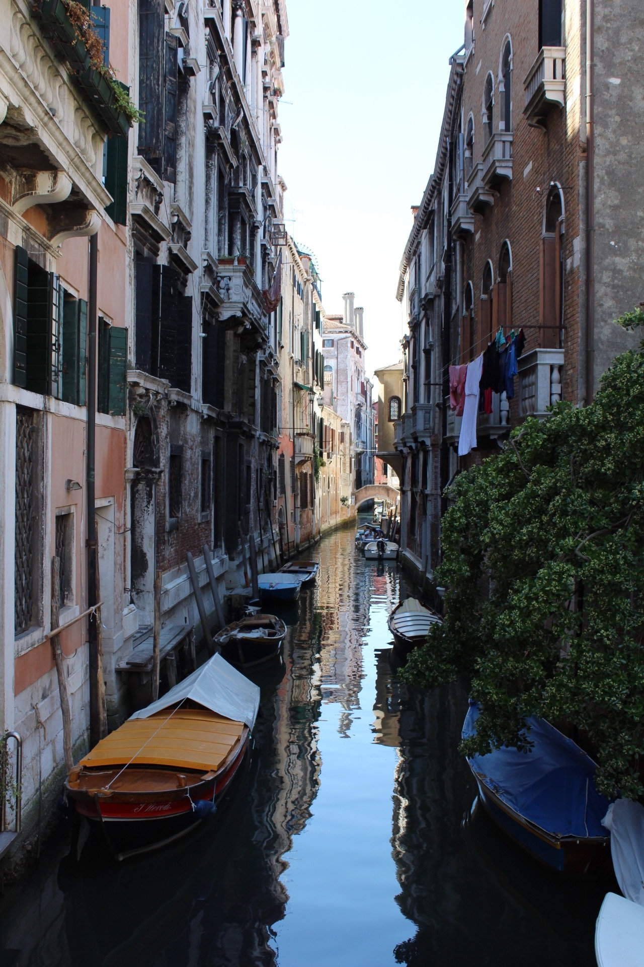 Narrow canal lined with old houses, moored boats and washing hanging from balconies