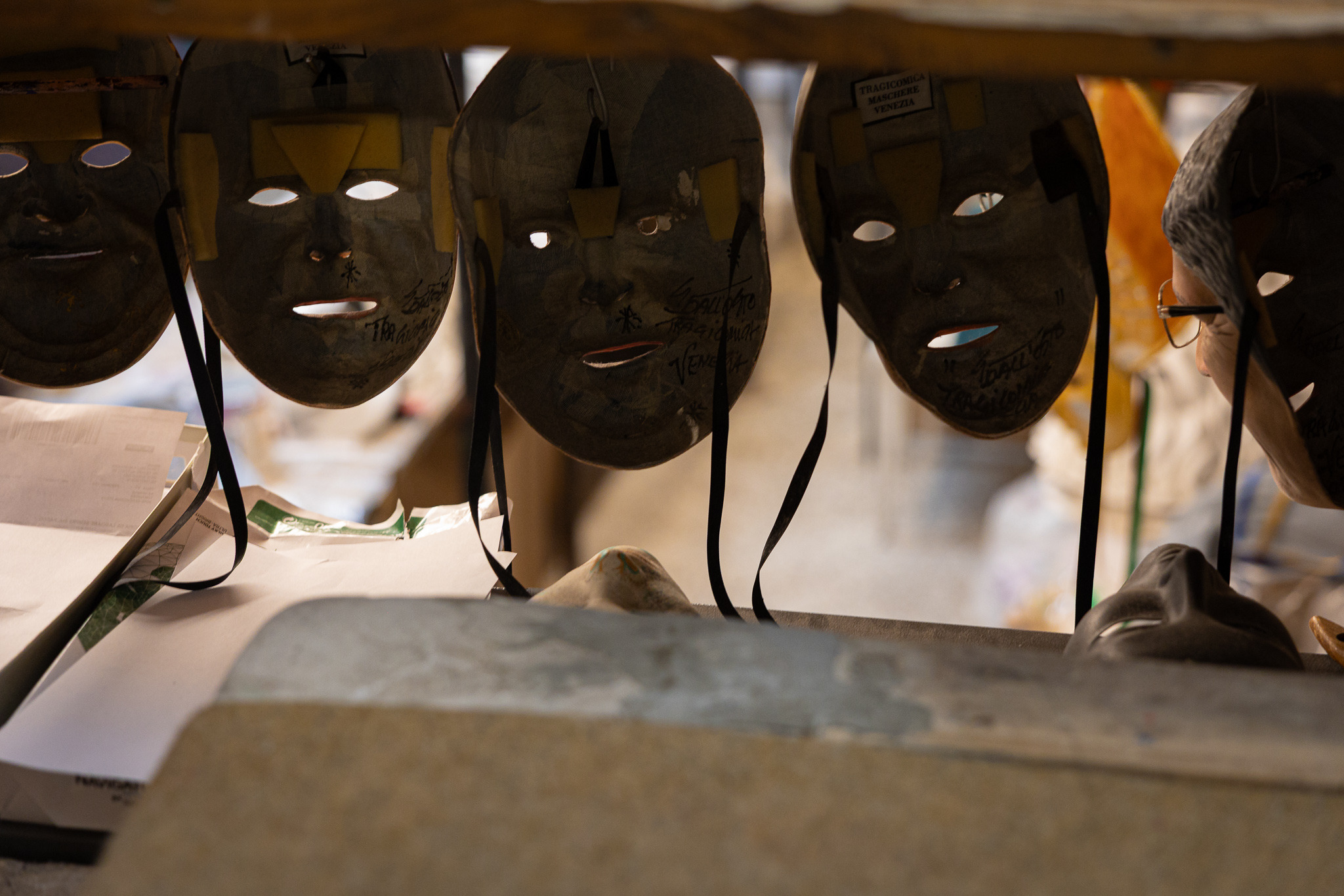 Row of plain papier-mâché masks hanging to dry in a mask-maker's workshop