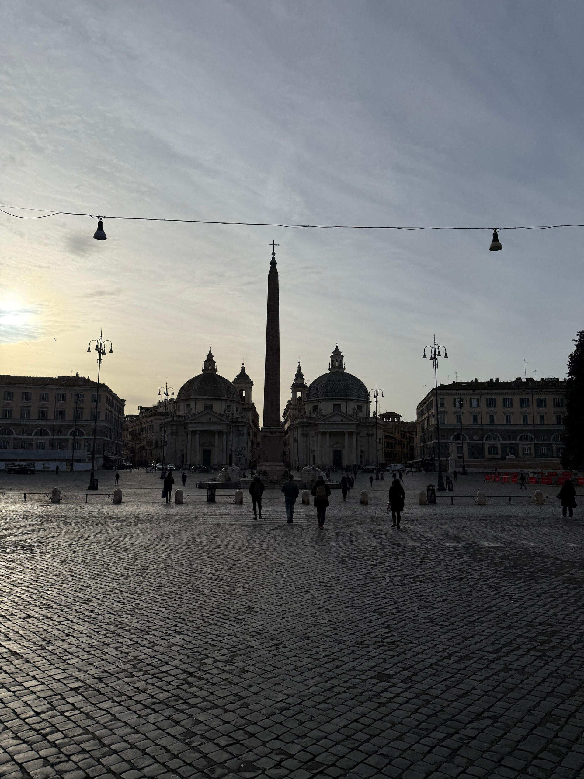 Piazza del Popolo in Rome at dusk with the obelisk and twin churches silhouetted against the sky