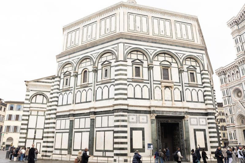 Black-and-white marble Baptistery of Florence with crowds in the piazza before it