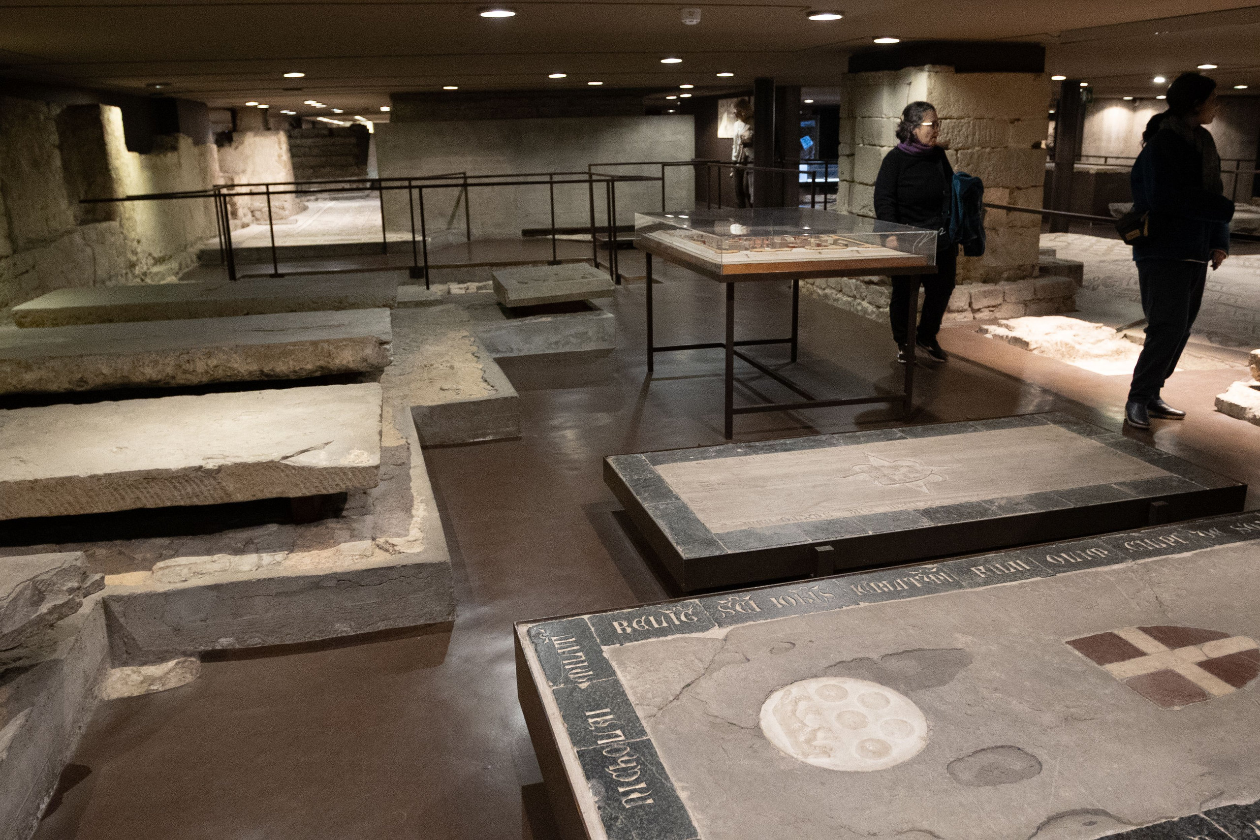 Underground archaeological area beneath the Duomo with ancient tombs and a visitor walking among them