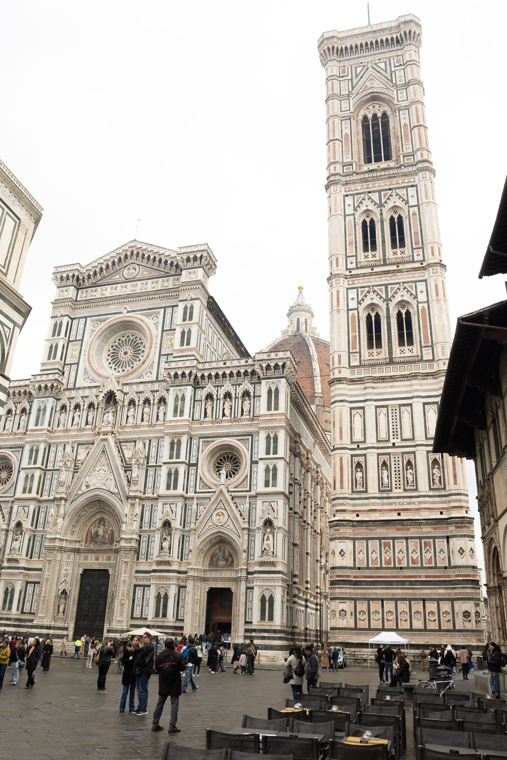 Cathedral facade and Giotto's bell tower rising above a piazza with cafe tables