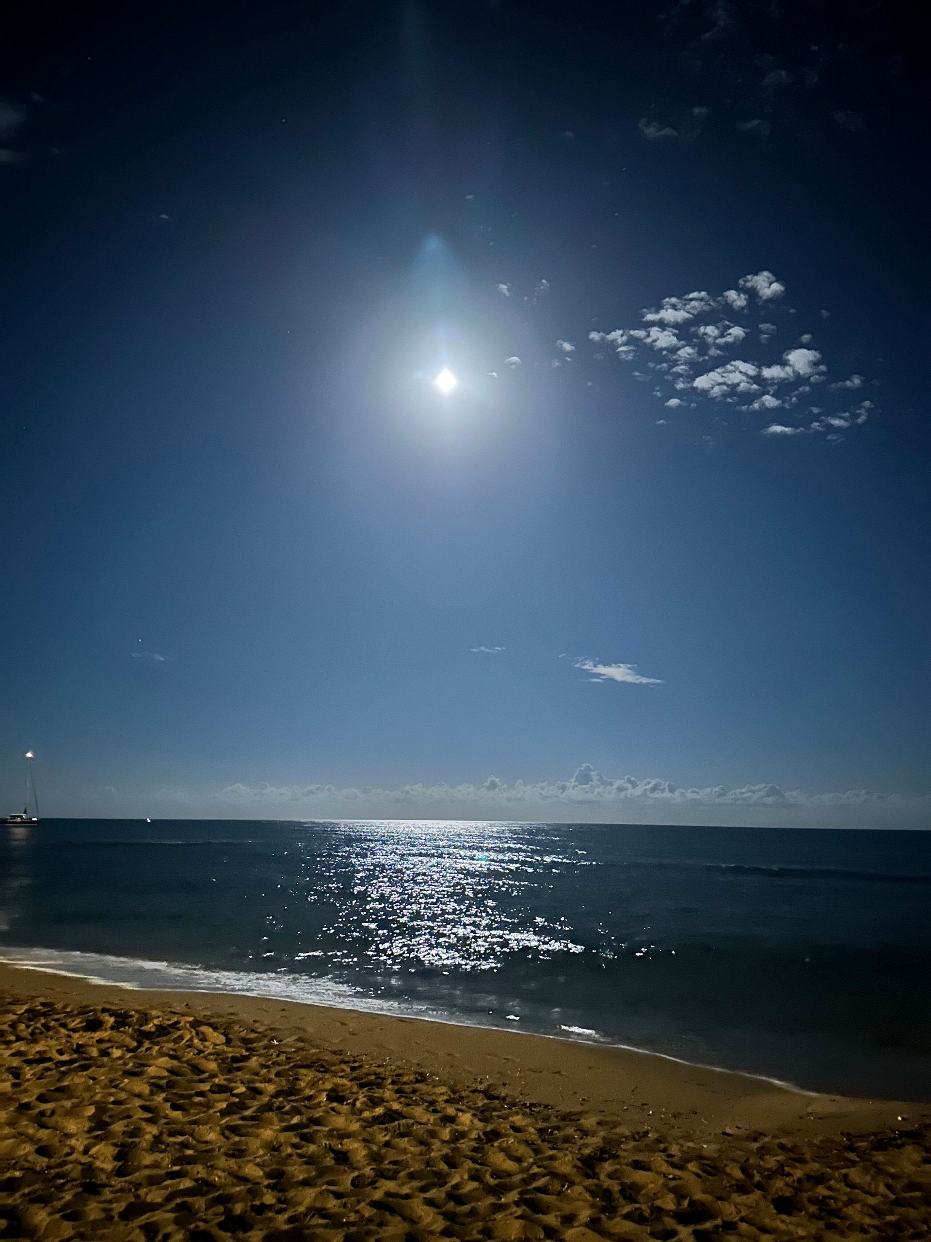 Full moon over a quiet beach in Sicily, with moonlight glittering on the sea