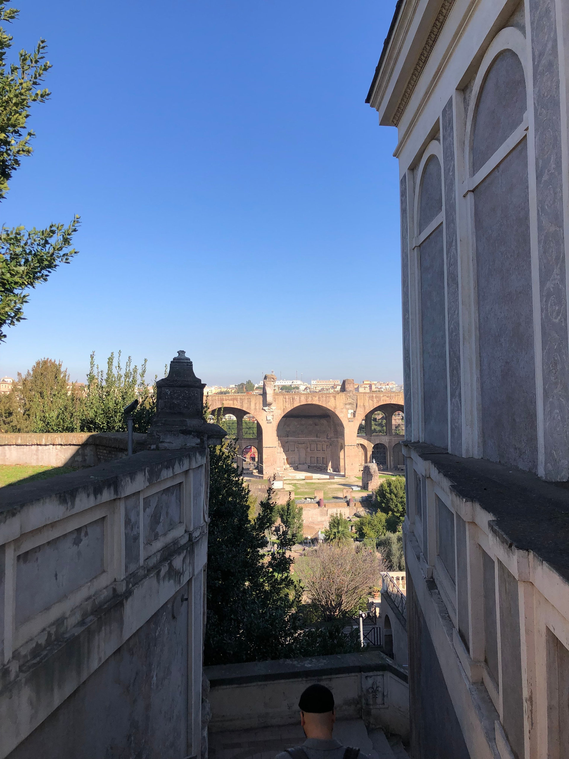 Looking down a stairway towards the vast brick arches of the Basilica of Maxentius