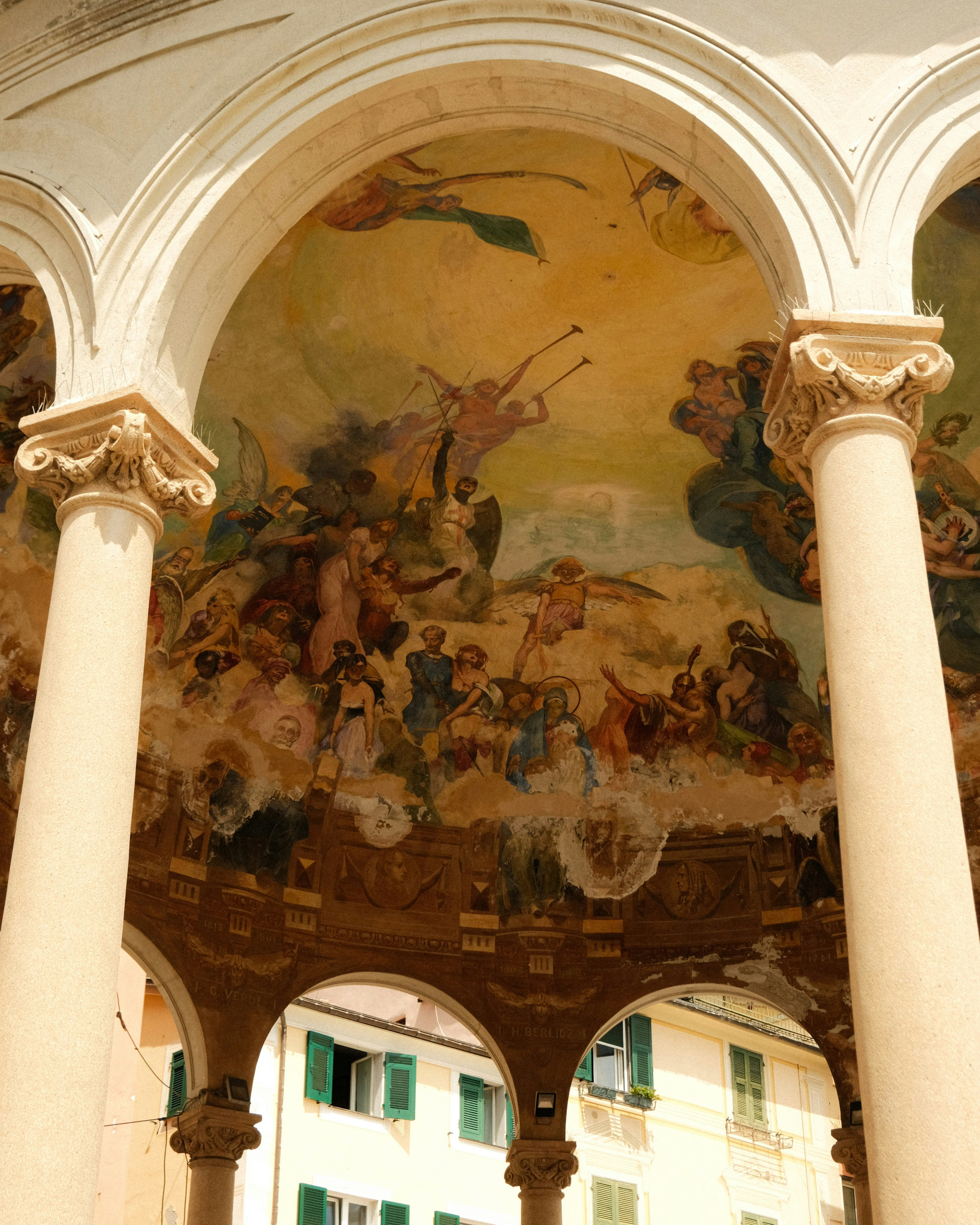 Frescoed vault of an arcaded loggia with angels, framed by two columns with carved capitals