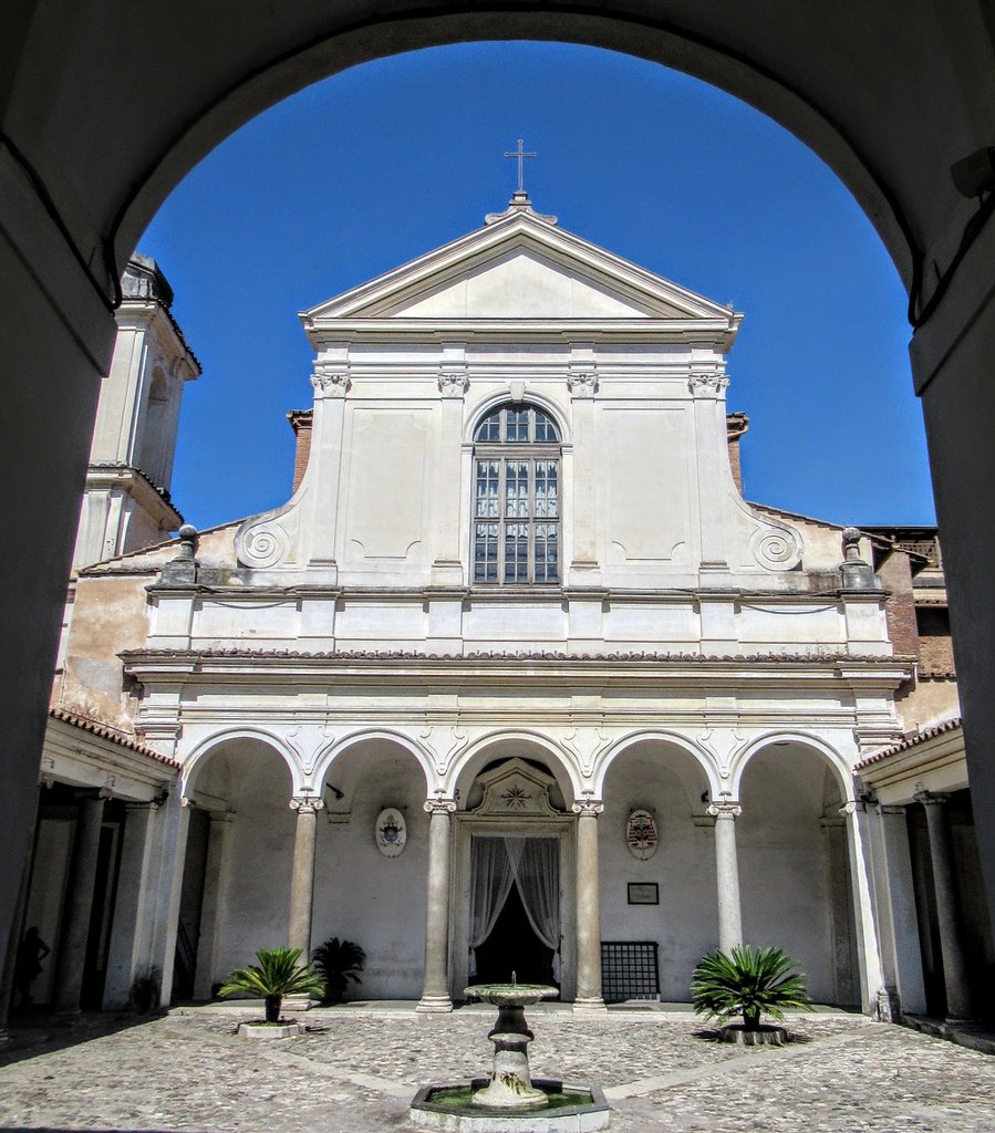 Church facade seen through an archway across a quiet courtyard with a small fountain