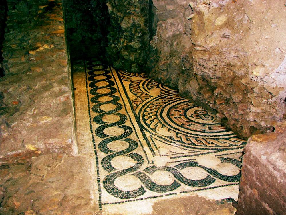 Black-and-white mosaic floor with spiral and wave patterns running along an excavated passage
