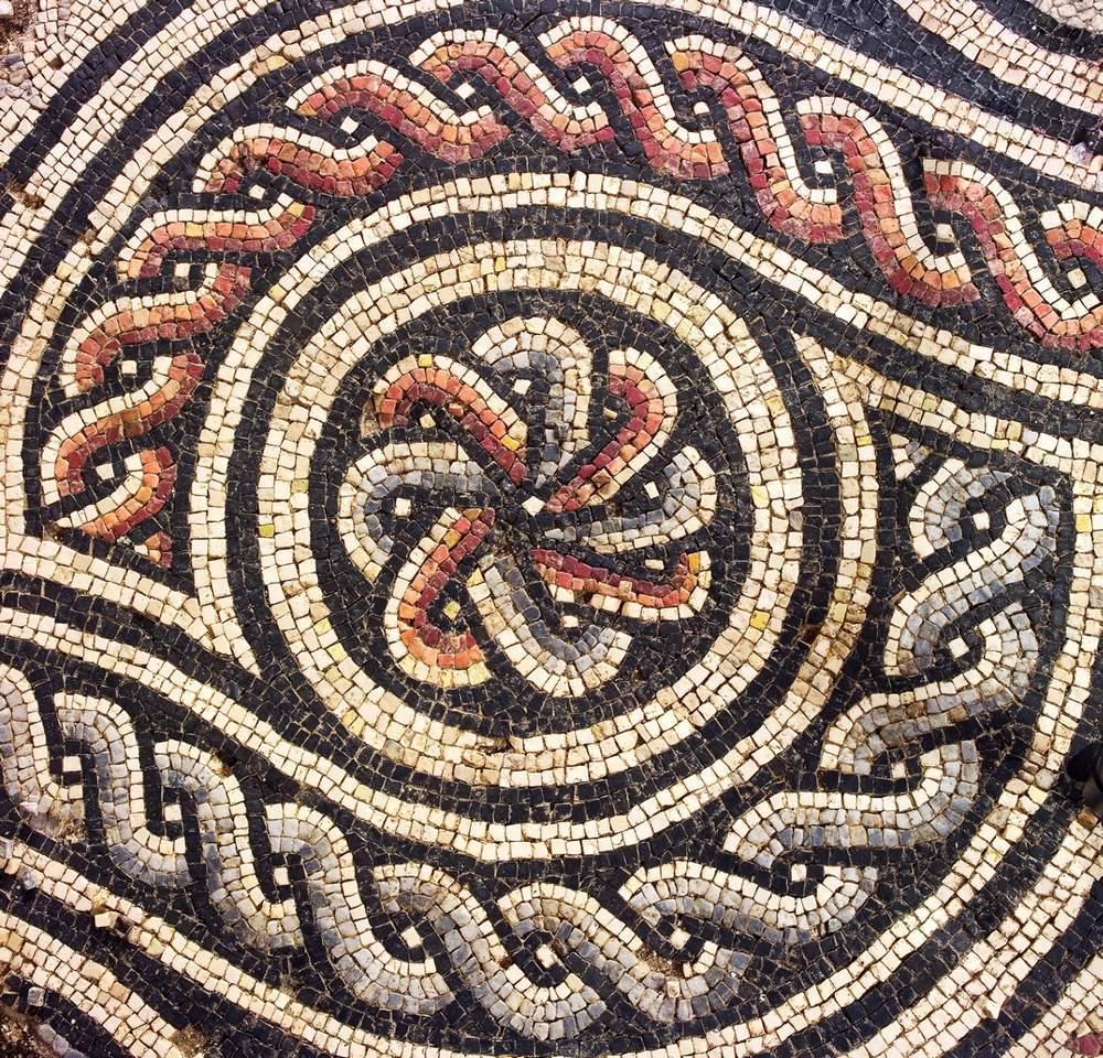 Detail of a Roman mosaic with interlaced braids and a rosette in red, grey and black tesserae