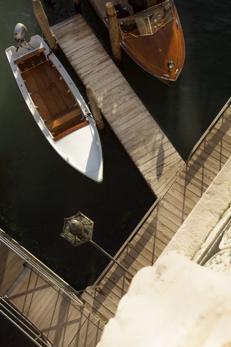 Wooden motorboats moored along a jetty on a Venetian canal, seen from above