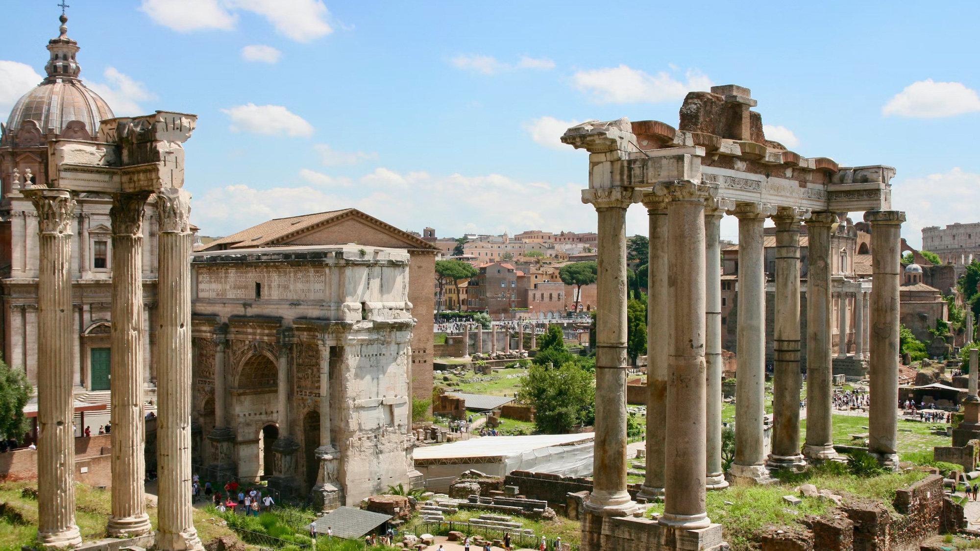 Ancient columns and the Arch of Septimius Severus in the Roman Forum under a blue sky