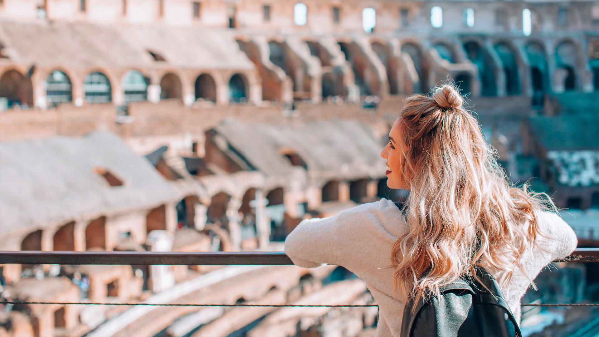 Traveller with a backpack leaning on a railing and looking across the Colosseum interior
