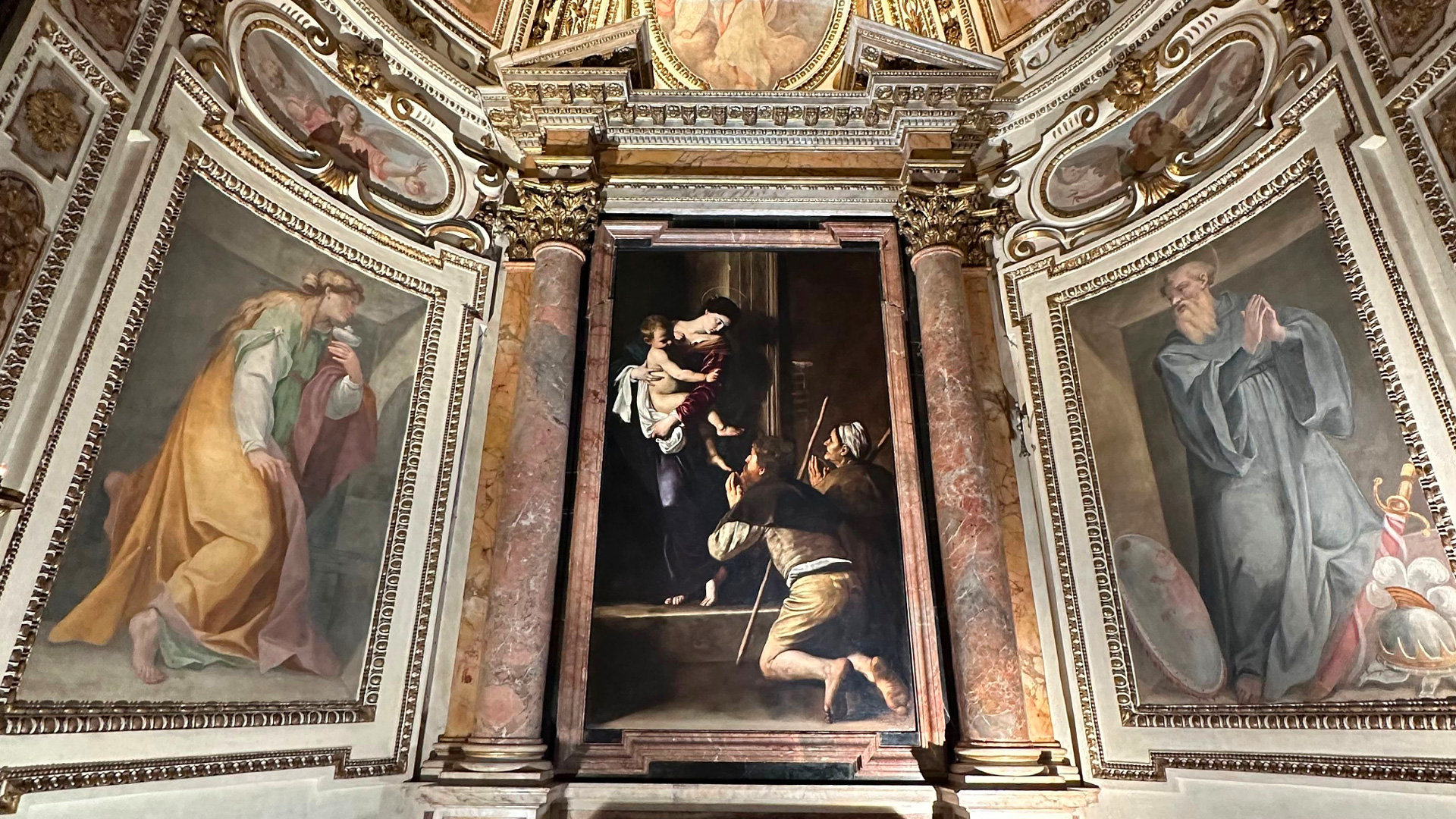 Chapel altar with Caravaggio's Madonna of the Pilgrims flanked by frescoed saints