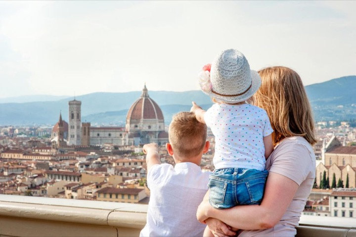 Mother and two children pointing at the Florence skyline and cathedral dome from a panoramic terrace