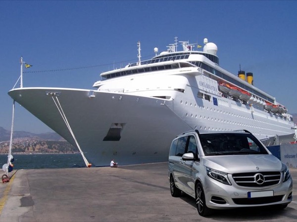 Silver minivan parked on the quayside next to a large white cruise ship