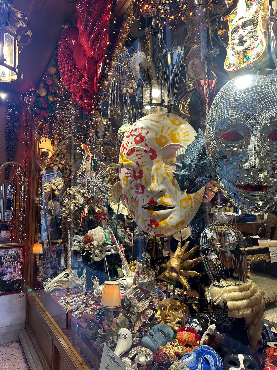 Venetian mask shop window packed with painted and mirrored masks, golden hands and lanterns