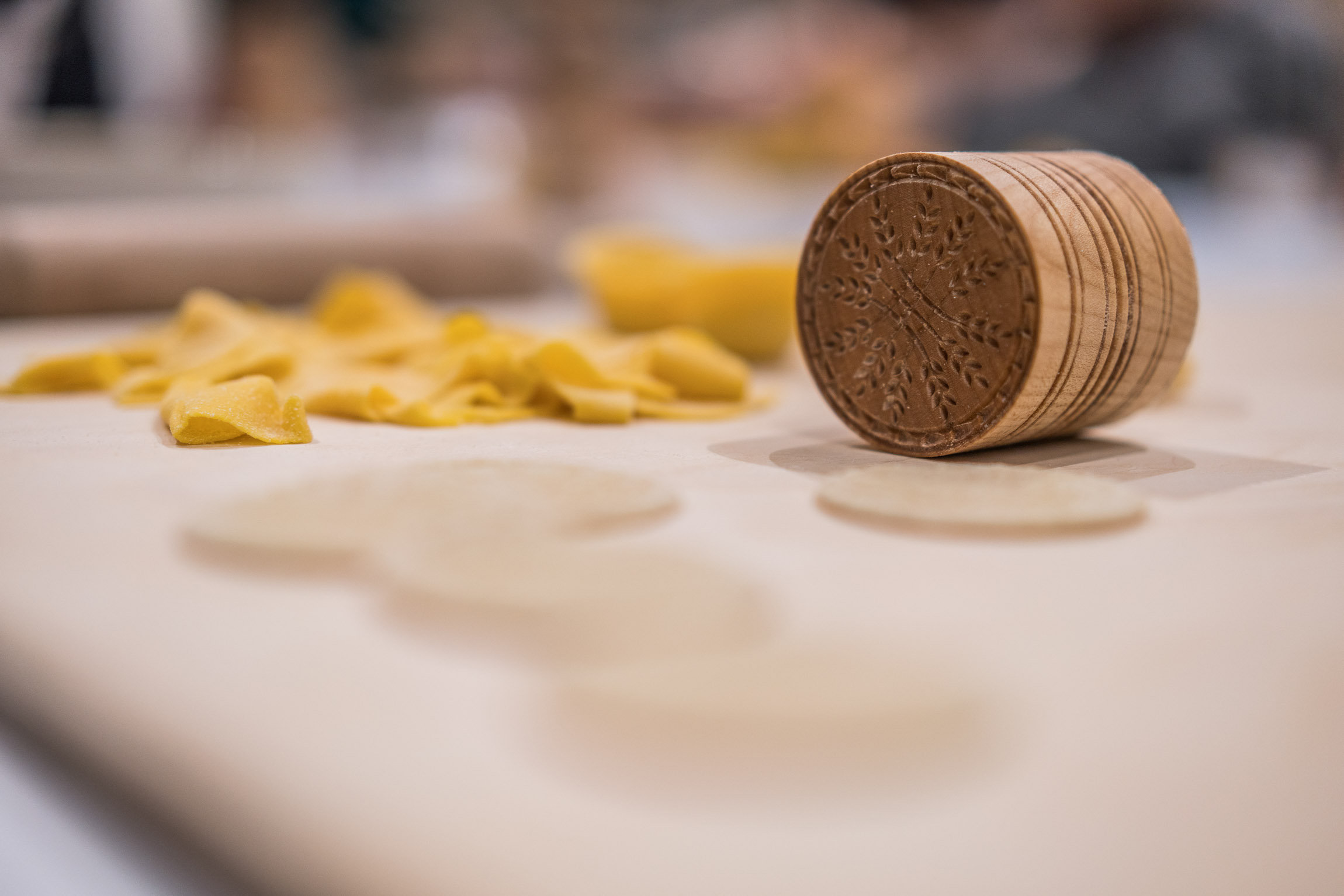 Fresh egg pasta and a carved wooden stamp on a floured board during a cooking class