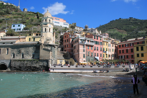 Colourful waterfront houses and a church bell tower on a small beach in a Cinque Terre village