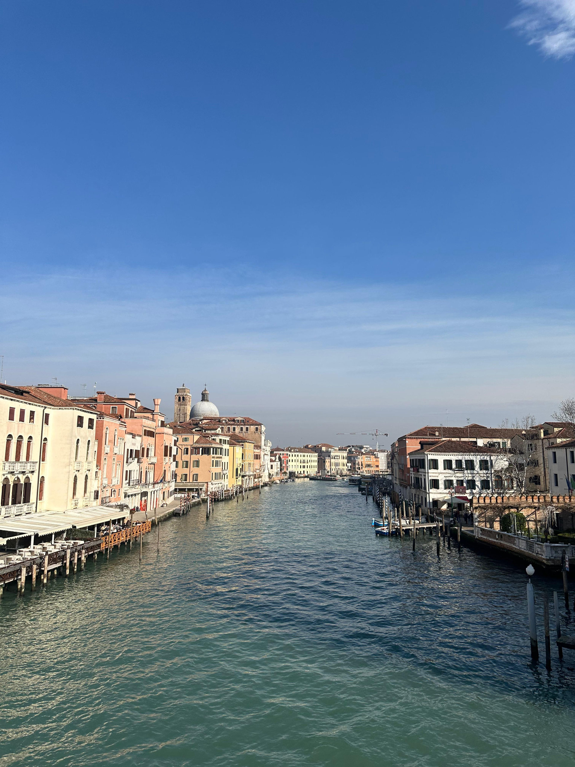 Grand Canal in Venice with pastel buildings and a domed church under a blue sky