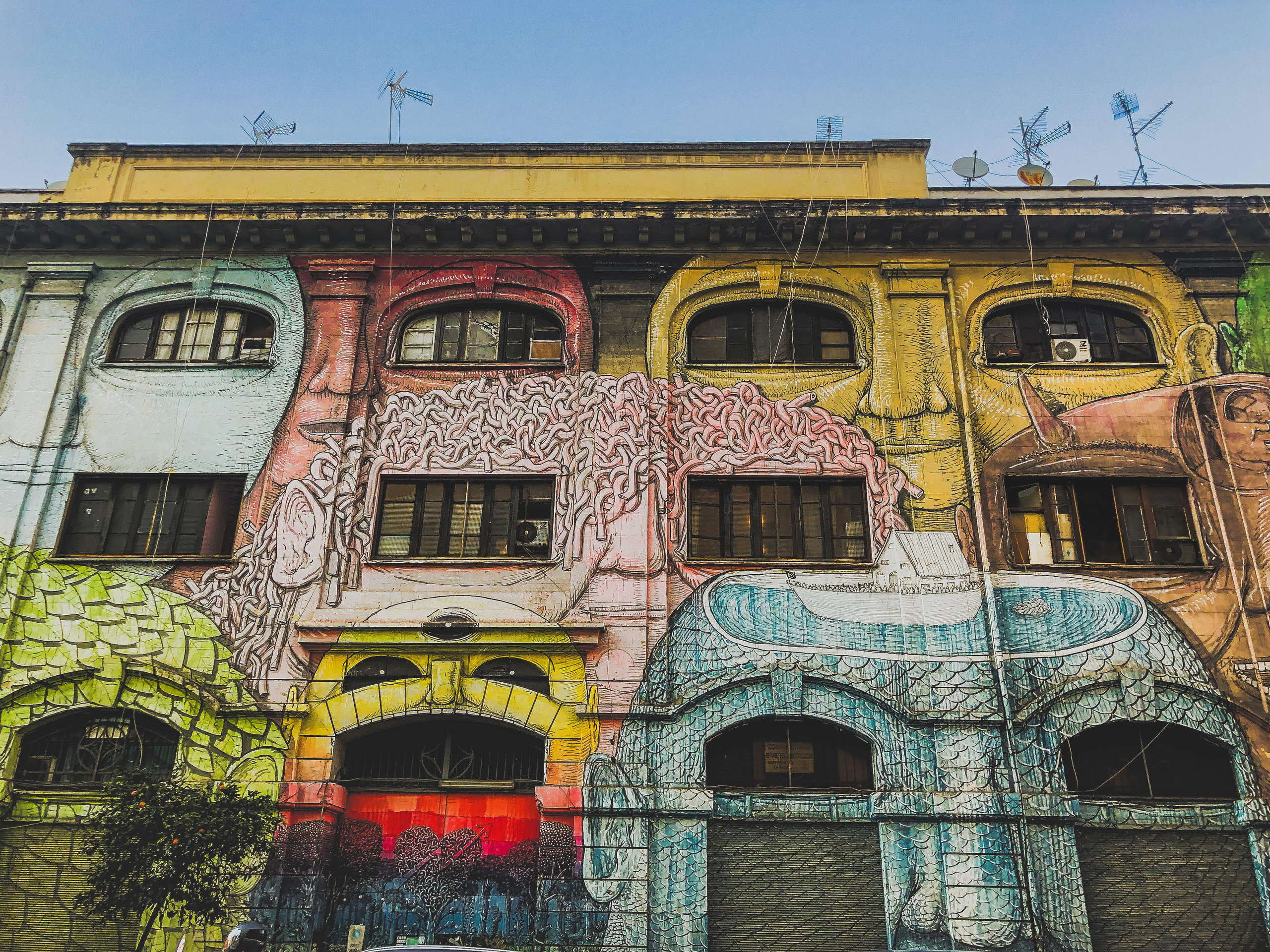 Building facade covered in a colourful mural of huge faces framed by its windows