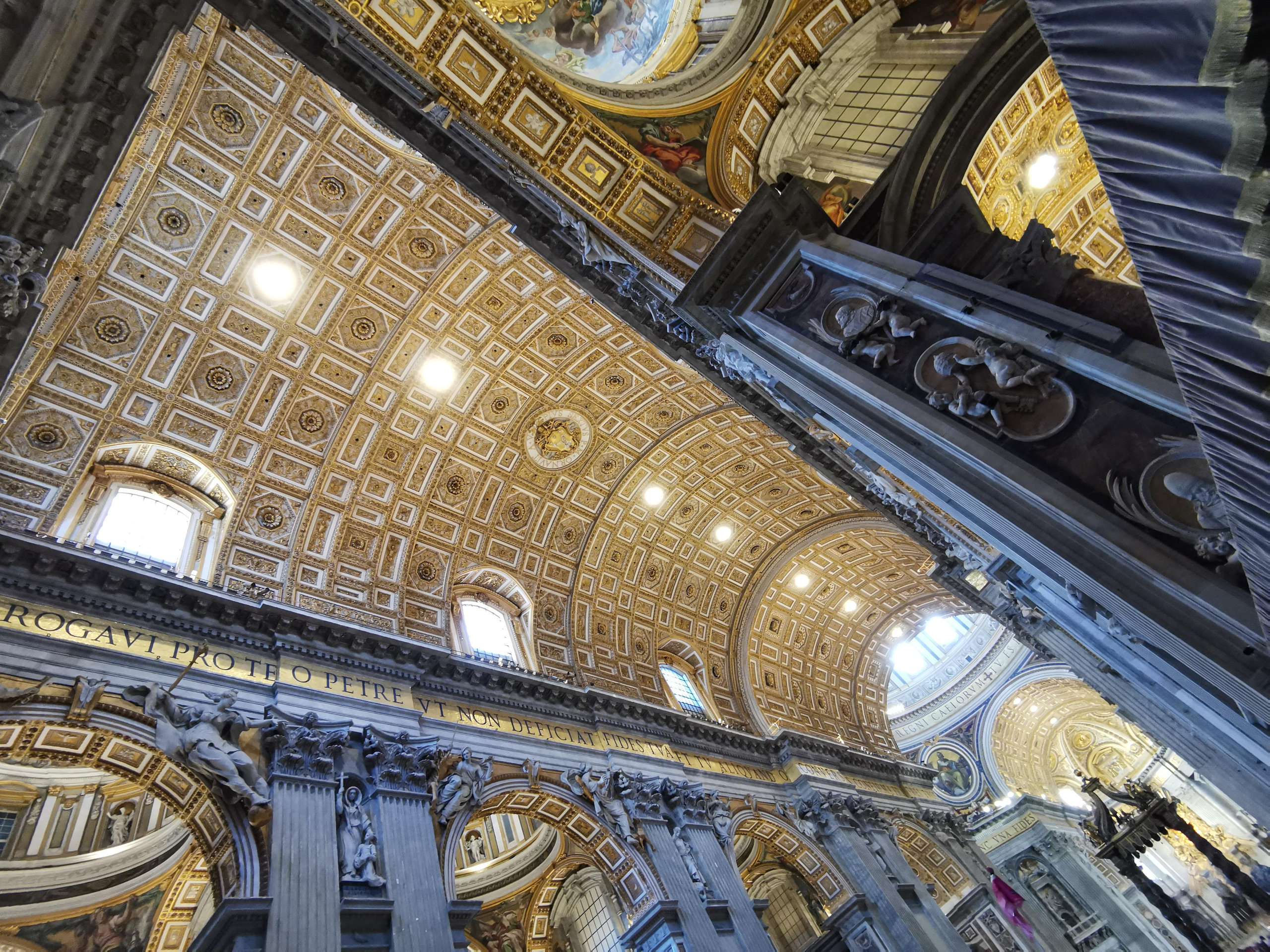 Looking up at the gilded coffered ceiling and carved pilasters inside Saint Peter's Basilica