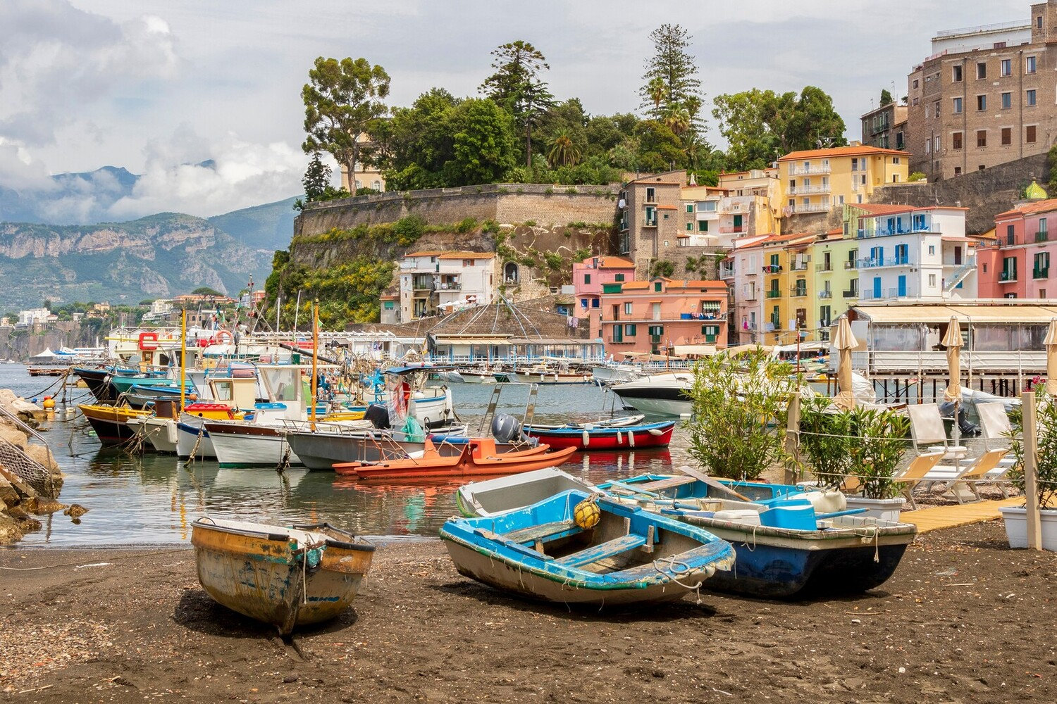 Small fishing boats pulled up on the beach of a colourful Sorrento harbour village